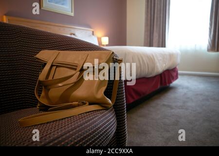 Ein Foto einer Handtasche auf einem Stuhl in einem Hotelzimmer. Stockfoto