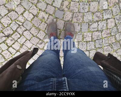 Über Kopf Aufnahme der Beine eines Mannes auf Kopfsteinpflaster stehen Gehweg Stockfoto