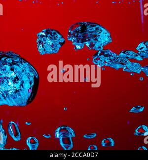 Nahaufnahme der kalten und frischen Cola mit hellen Blasen im Neonlicht. Textur des kühlenden Sommergetränks mit Makroblasen auf Glas. Spritzt oder schwimmt bis zur Oberfläche, spritzt Flüssigkeit. Stockfoto