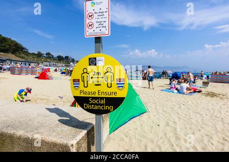 Am Strand anmelden: Bitte sorgen Sie für soziale Distanzierung, bei Lyme Regis, einem beliebten Badeort an der Jurassic Coast in Dorset, SW England Stockfoto