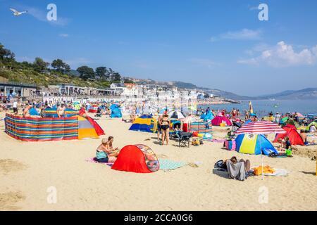 Der überfüllte Strand und das Meer in der Hochsaison bei Lyme Regis, einem beliebten Badeort an der Jurassic Coast in Dorset, Süd-West-England Stockfoto