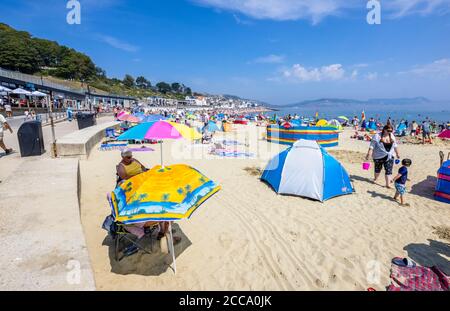 Der überfüllte Strand und das Meer in der Hochsaison bei Lyme Regis, einem beliebten Badeort an der Jurassic Coast in Dorset, Süd-West-England Stockfoto