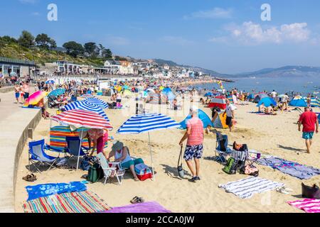 Der überfüllte Strand und das Meer in der Hochsaison bei Lyme Regis, einem beliebten Badeort an der Jurassic Coast in Dorset, Süd-West-England Stockfoto