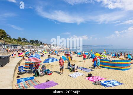 Der überfüllte Strand und das Meer in der Hochsaison bei Lyme Regis, einem beliebten Badeort an der Jurassic Coast in Dorset, Süd-West-England Stockfoto