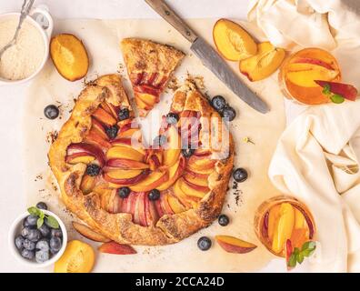 Köstliche Pfirsich-Galette und Heidelbeere auf einem Pergamentpapier platziert. Draufsicht flach liegend. Stockfoto