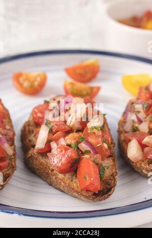 Mediterrane Bruschetta mit Tomate, Olivenöl, Petersilie und roter Zwiebel auf weißem Hintergrund. Stockfoto