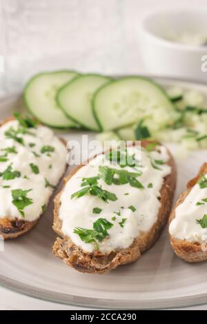 Mediterrane Bruschetta mit Zatziki, Gurke und Petersilie. Serviert und fertig zum Essen. Nahaufnahme. Stockfoto