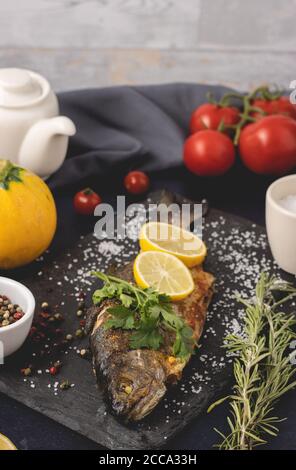 Gegrillte Forelle mit Olivenöl, Petersilie, Pfeffer, Salz und Zitrone auf den dunklen Hintergrund gelegt. Gesunde Ernährung und Diät-Konzept. Bereit zum Essen. Stockfoto