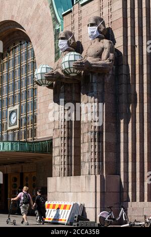 Kugelförmige Lampe mit Skulpturen am Haupteingang des Hauptbahnhofs mit Gesichtsmasken während der COVID-19 Pandemie in Helsinki, Finnland Stockfoto