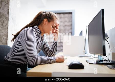 Überarbeitet und frustrierte junge Frau vor der Computer im Büro Stockfoto