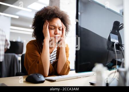 Überarbeitet und frustrierte junge Frau vor der Computer im Büro Stockfoto