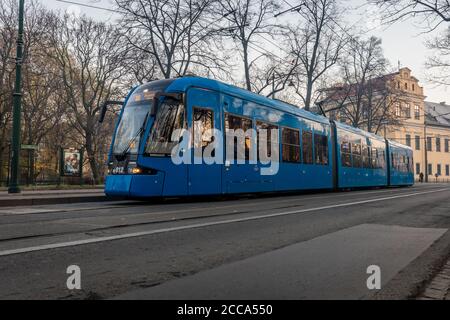 Eine moderne Straßenbahn fährt an einem Park im Zentrum von Krakau vorbei In Polen Stockfoto