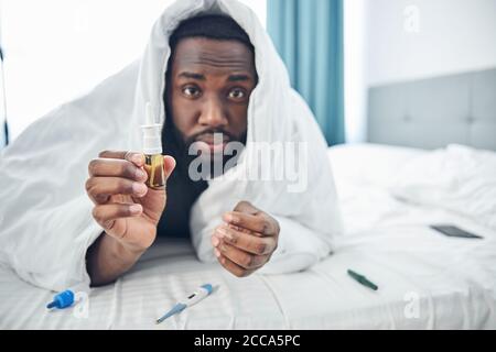 Konzentrierter junger Mann, der seine Tropfen für die Nase vorführt Stockfoto