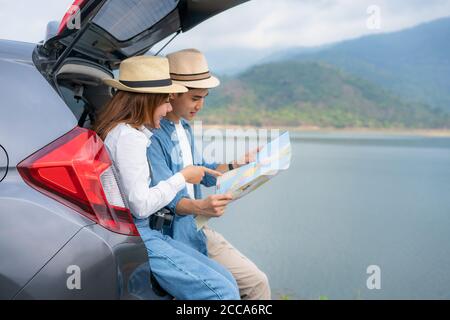 Portrait von asiatischen Paar sitzen im Auto mit Mann und Frau suchen schöne Landschaft und halten Karten während Urlaub zusammen im Urlaub. Happy roma Stockfoto