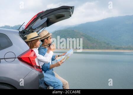 Portrait von asiatischen Paar sitzt im Auto mit Mann halten Karten und Frau, die ein Foto schöne Landschaft mit der Kamera Während Urlaub zusammen in holida Stockfoto