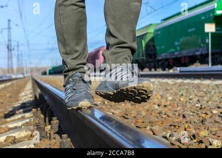Ein freier Mann, der auf einem Eisenbahngleis in Dirty läuft Schuhe und Hosen Stockfoto