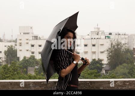 Indische Frau mit Regenschirm im Regen. Blick in die Kamera. Stockfoto