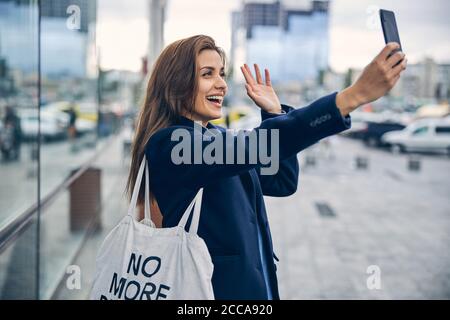 Junge schöne Dame lachend und winkende Hand in der Kamera Stockfoto