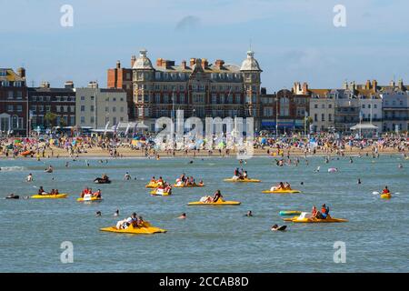 Weymouth, Dorset, Großbritannien. August 2020. Wetter in Großbritannien. Urlauber genießen eine Fahrt auf Pedalos auf dem Meer mit dem vollen Strand hinter ihnen im Badeort Weymouth in Dorset an einem windigen Tag mit sengenden heißen Sonnenschein und klaren blauen Himmel. Bild: Graham Hunt/Alamy Live News Stockfoto