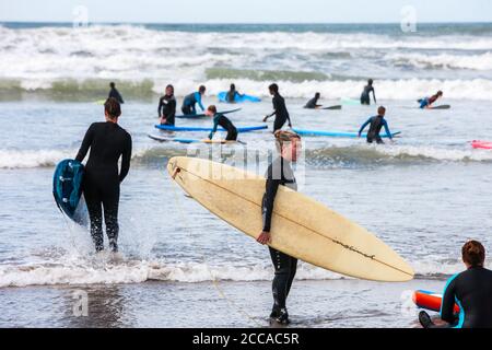 Beschäftigt, überfüllt, Borth, Borth Beach, mit, ein, riesig, Zustrom, von, Touristen, vor allem, aus, England, Englisch, auf, windig, Tag, mit, Böen, vor, zu, ein, Sturm, machen, groß, Surfen, Surfen, Bedingungen, und kompetent, Surfer, und, Anfänger, nehmen, zu, die, Wasser, Wasser. Gelegen, an, Cardigan Bay, nördlich, von, Aberystwyth, Borth Beach, erstreckt sich für, viele, Meilen, nach, Ynyslas, und ist ein beliebter Surfspot. Die, Menschenmassen, sind, besonders groß, weil viele Briten bleiben Aufenthalt in diesem Jahr. Stockfoto