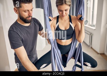 Fokussierte blonde Frau, die in einer Hängematte sitzt Stockfoto