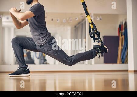 Sportlicher junger Mann mit TRX-Ausfallschritt Stockfoto