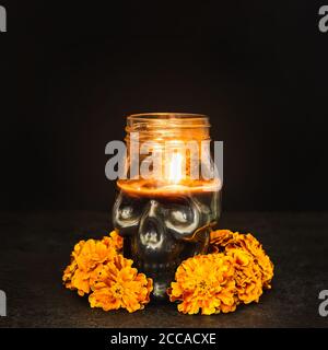 Brennende Kerze Totenkopf mit Ringelblumen auf schwarzem Hintergrund. Dia de los muertos Tag oder Tag der Toten. Stockfoto