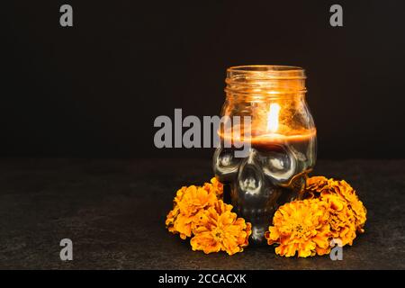 Brennende Kerze Totenkopf mit Ringelblumen Kranz auf schwarzem Hintergrund. Dia de los muertos Tag oder Tag der Toten. Stockfoto