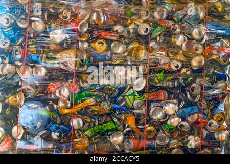 Abstrakter Hintergrund von bunten komprimierten Aluminiumdosen in Behälter zum Recycling gelagert. Konzept von Recycling, Ökologie, Umweltverschmutzung Stockfoto