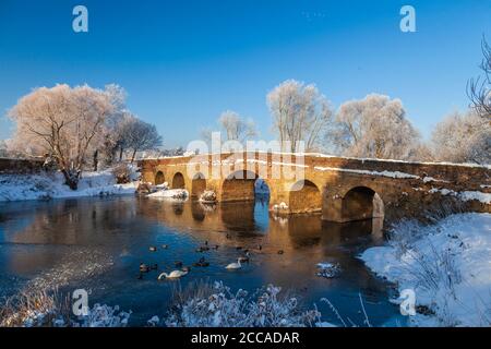 Der Schnee bedeckte 15. Jahrhundert Pershore Alte Brücke über den gefrorenen Fluss Avon, Worcestershire, England Stockfoto