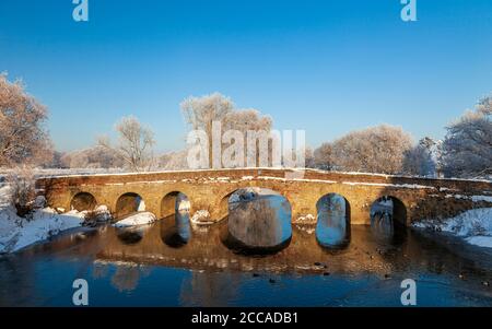 Der Schnee bedeckte 15. Jahrhundert Pershore Alte Brücke über den Fluss Avon, Worcestershire, England Stockfoto