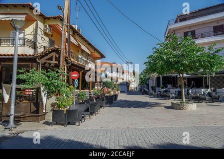 Chalkidiki, Griechenland nach neuen covid-19 Maßnahmen fast leere Kaffeesessel und Tische. Tagsüber Sitzbereich im Freien mit ein paar Kunden im Hanioti Dorf. Stockfoto