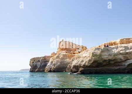 Lagoa, Portugal - 11. Juli 2020: Menschen, die von den Klippen der Region Lagoa fischen. Küstenlinie aus hoch aufragenden Klippen, türkisfarbenem Wasser und Bild Stockfoto