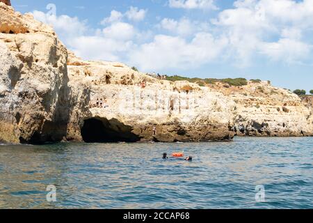 Lagoa, Portugal - 11. Juli 2020: Menschen springen in das Wasser von den Klippen der Region Lagoa und andere Tauchen. Küste aus Toweri gebildet Stockfoto