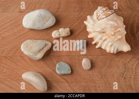 Die glatten Steine verschiedener Umfänge und die Schale auf dem Hintergrund eines Holzbretts Stockfoto