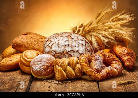 Brotauswahl auf einem rustikalen Holztisch. Verschiedene Brot- und Weizenohren. Studioaufnahme. Stillleben. Stockfoto