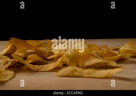 Appetitliche Kartoffelchips sind auf einem Holzbrett verstreut Stockfoto