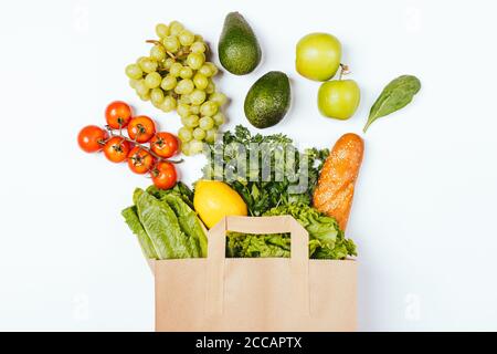 Ausgewogene Ernährung Lebensmitteleinkauf Papiertüte mit frischem Obst, Gemüse, Kräutern und knusprigen Vollkornbrot auf weißem Hintergrund. Stockfoto