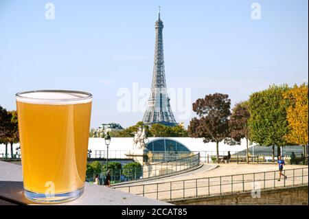 Ein Glas helles Bier auf dem Eiffelturm verwischen den Hintergrund. Sonniger Blick auf ein Glas Rotwein mit Blick auf den Eiffelturm in Paris, Frankreich Stockfoto