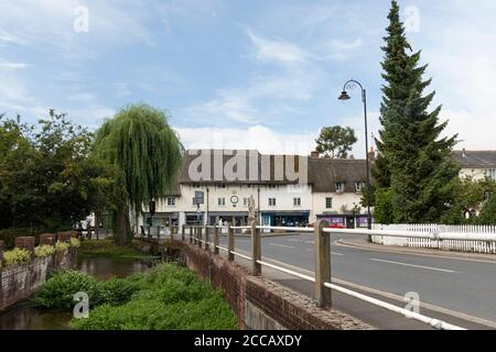 Der Fluss Avon fließt durch das Zentrum von Pewsey Dorf mit König Alfred Statue und Phoenix Row strohgedeckten Gebäuden im Hintergrund, Wiltshire, Großbritannien Stockfoto