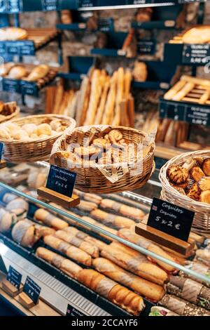 Brotladen-Schaufenster. Geflochtene Körbe mit verschiedenen Brötchen, Regale mit Brot und ein Schaufenster mit Sandwiches. Stockfoto