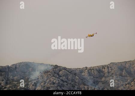 Ein Löschwasserbomber, der Wasser auf einen Waldbrand auf dem Berg Kozjak in Kroatien abtropft. Sommer Waldbrände sind sehr häufig in der trockenen und Stockfoto