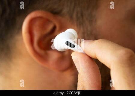 Izmir, Türkei - 7. August 2020: Nahaufnahme von weißen Apple AirPods auf dem Ohr eines Mannes. Stockfoto