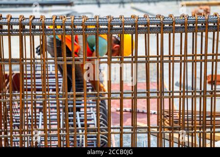 Bauarbeiter hinter der Bewehrungsstange, Stahlbefestiger, der Stahlverstärkungskäfig zusammenbindet. Stockfoto