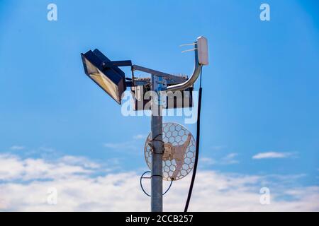 WLAN-Antenne auf einem Metalllichtmast im Freien mit blauem Himmel Hintergrund. Stockfoto