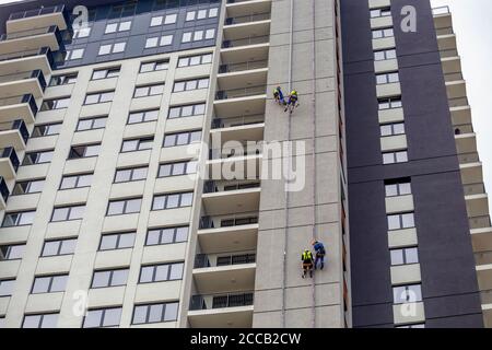 Arbeiter hängen am Gebäude und machen Elektroinstallationen in Wohngebäuden. Männer bei der Arbeit. Stockfoto