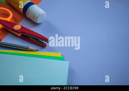 Ordentlich verlegte Schreibwaren zusammen mit einem Stapel anderer Papiere auf blauem Karton, um sich auf den Schulunterricht, das Stillleben, das Konzept, zurück zur Schule vorzubereiten Stockfoto
