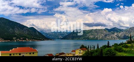 Luftaufnahme von Wohngebäuden entlang der Küste der Bucht von Kotor und Berge im Hintergrund im Sommer in Dobrota, Montenegro Stockfoto