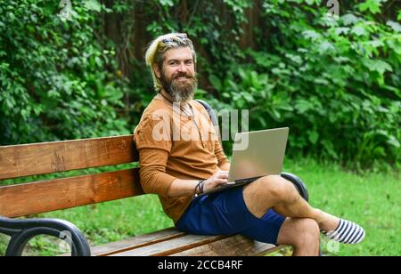 Business-Mann arbeiten im Freien mit Computer. Starten Sie Videokonferenzen. Kommunikation per Videoanruf. Geschäftsmann mit Laptop auf Bank im Park. Hübscher Mann, der am Laptop arbeitet. Mit modernen Technologien. Stockfoto