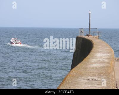 Blick auf das Meer und ein Fischerboot, das den Hafen verlässt; Blick vom Ende des Piers auf St Andrews, Fife, Schottlands Ostküste. Stockfoto